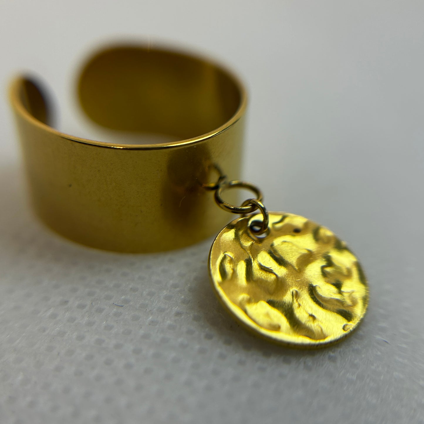 Gold ring with a textured coin charm